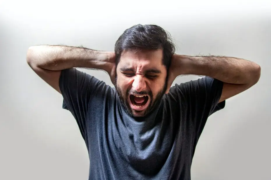 Un homme qui se tient la tête avec les mains et hurle